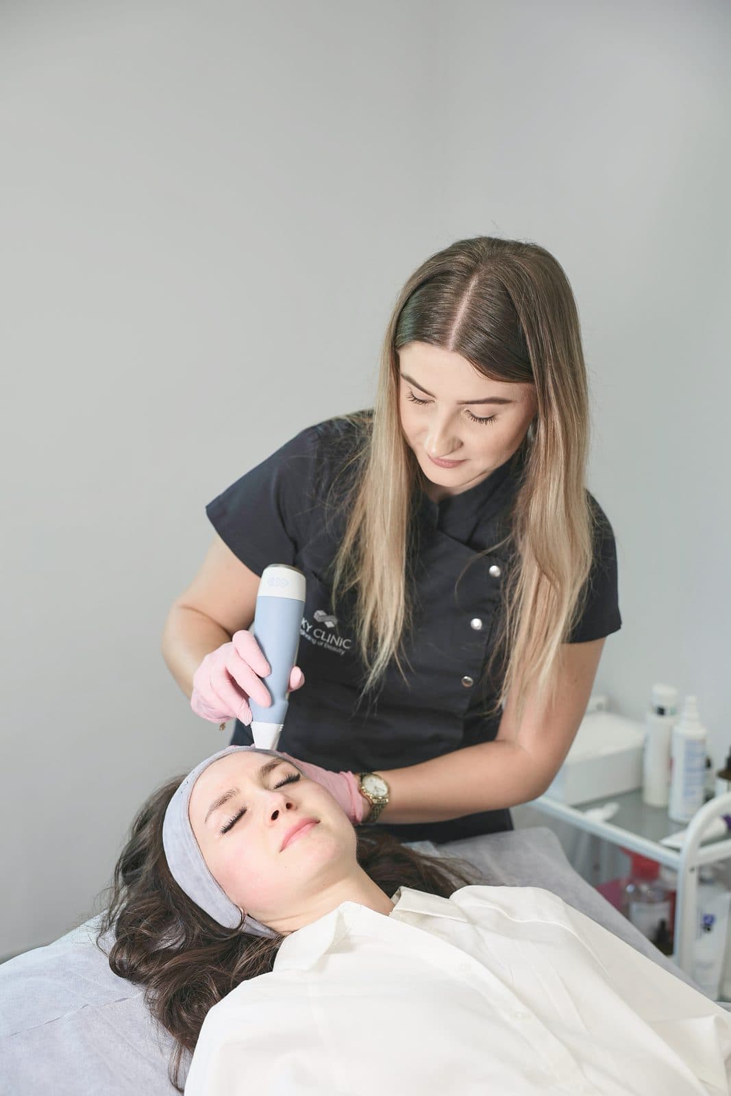 Kosmetolożka SkyClinic podczas zabiegu EXION, Pacjentka leży zrelaksowana z zamkniętymi oczami
