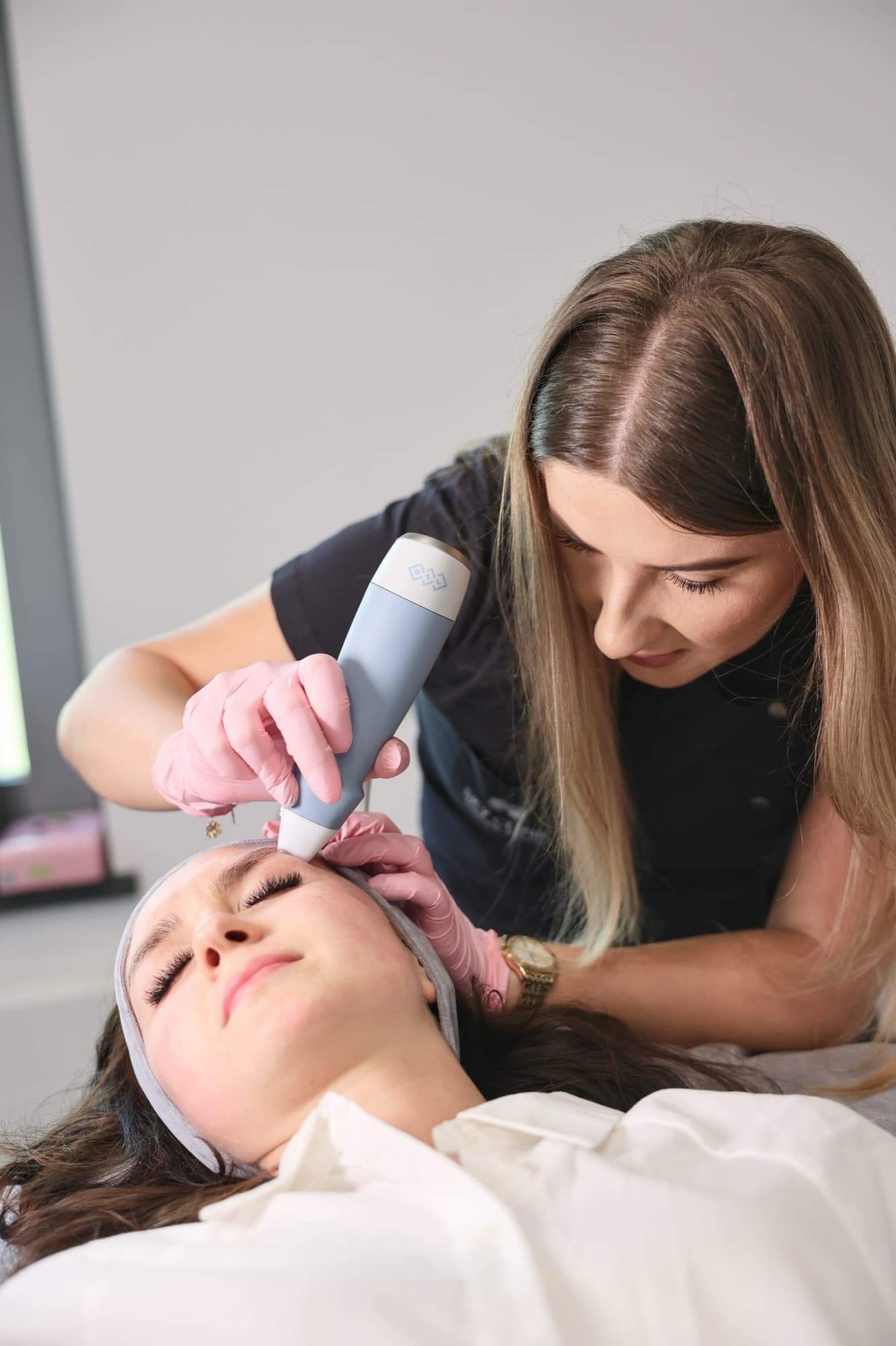 Kosmetolożka SkyClinic wykonuje zabieg EXION na czole Pacjentki